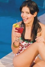 woman sipping cocktail by pool